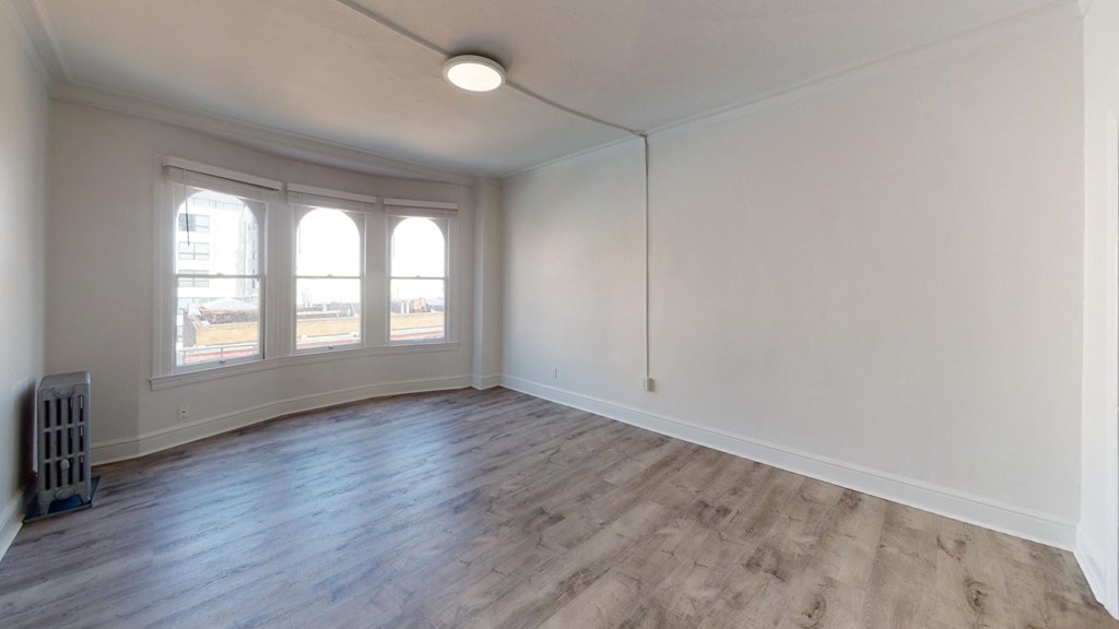 an empty living room with white walls and wood floors