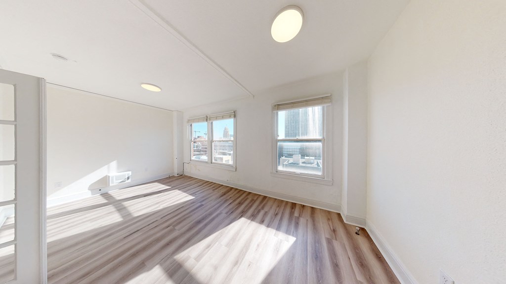 a living room with white walls and wood floors and a window
