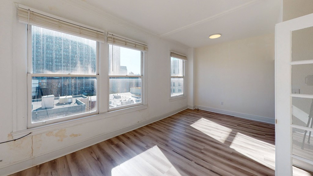 an empty living room with three windows and a wooden floor