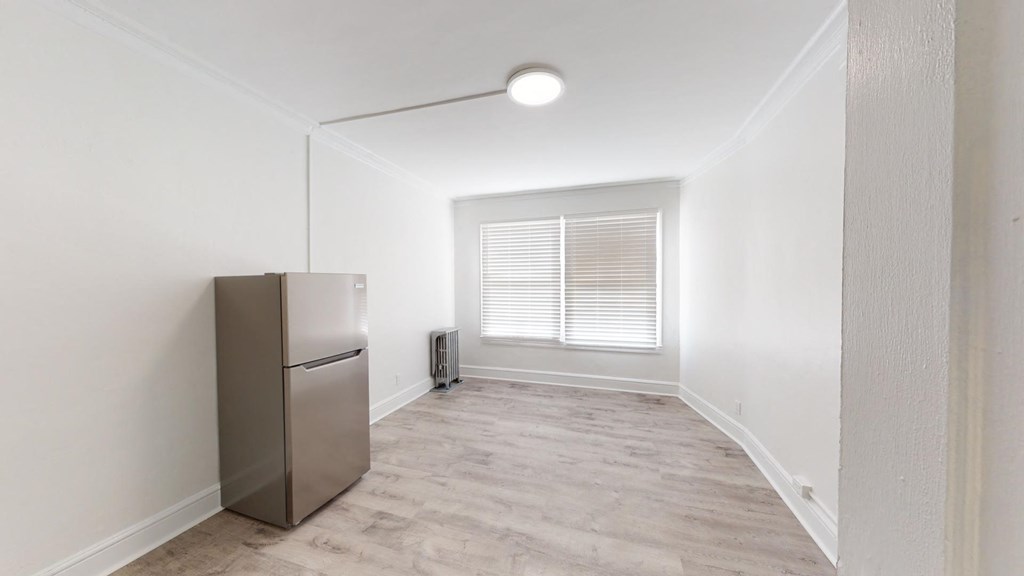 an empty room with a refrigerator and a window