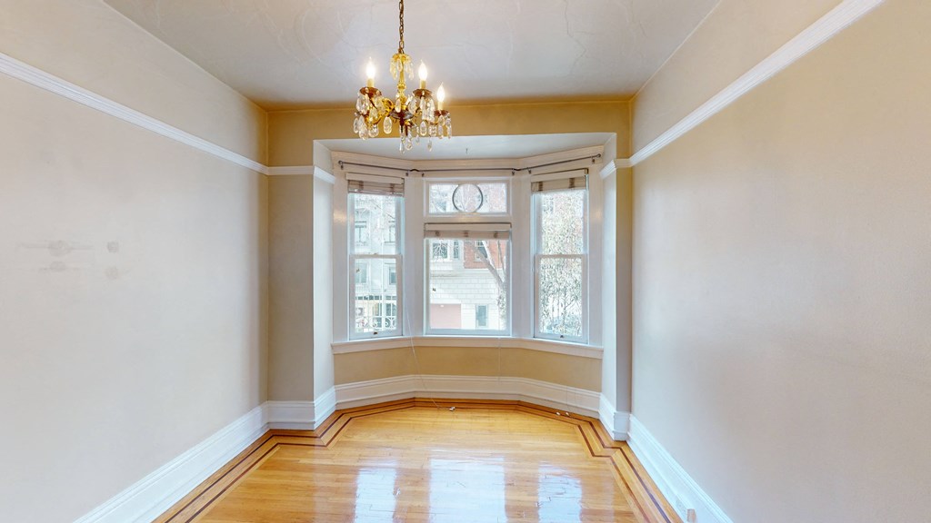 an empty living room with a large window and a chandelier