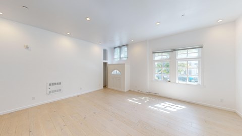 an empty living room with white walls and wood floors