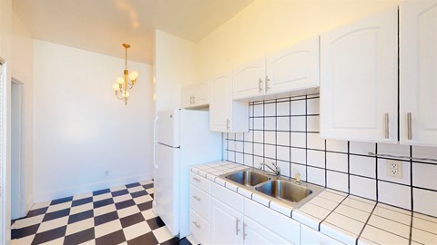 a kitchen with white cabinets and a black and white checkered floor
