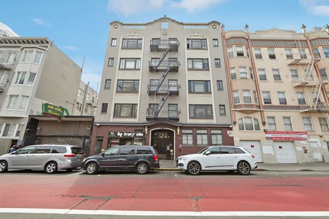 A street view of a city with cars parked and buildings in the background.