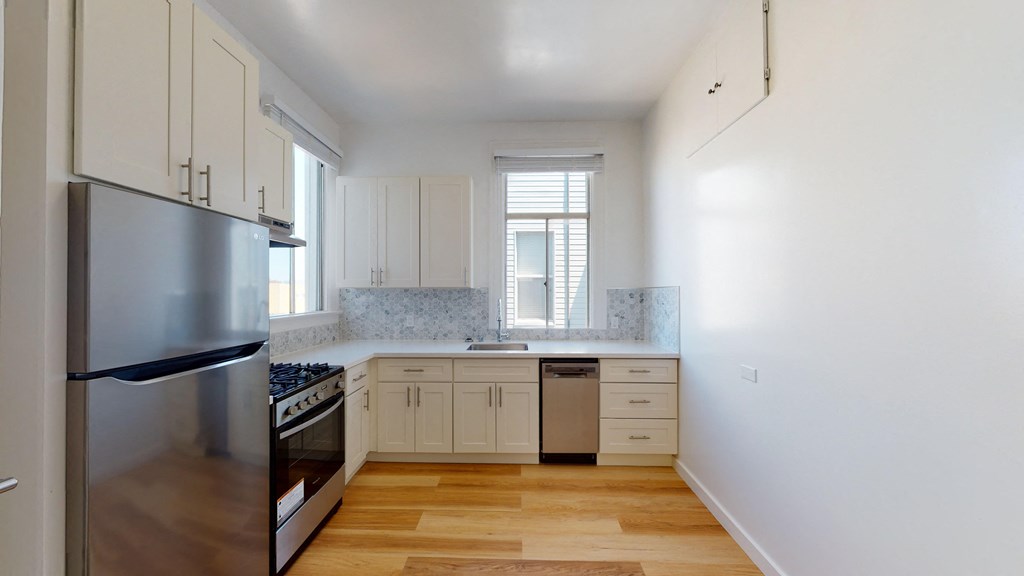 an empty kitchen with white cabinets and stainless steel appliances