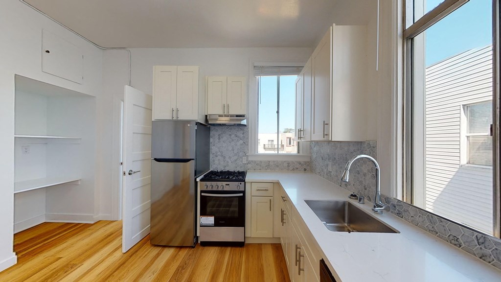 a kitchen with white cabinets and a sink and a window