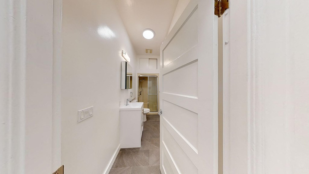 a hallway with a door to a bathroom and a sink