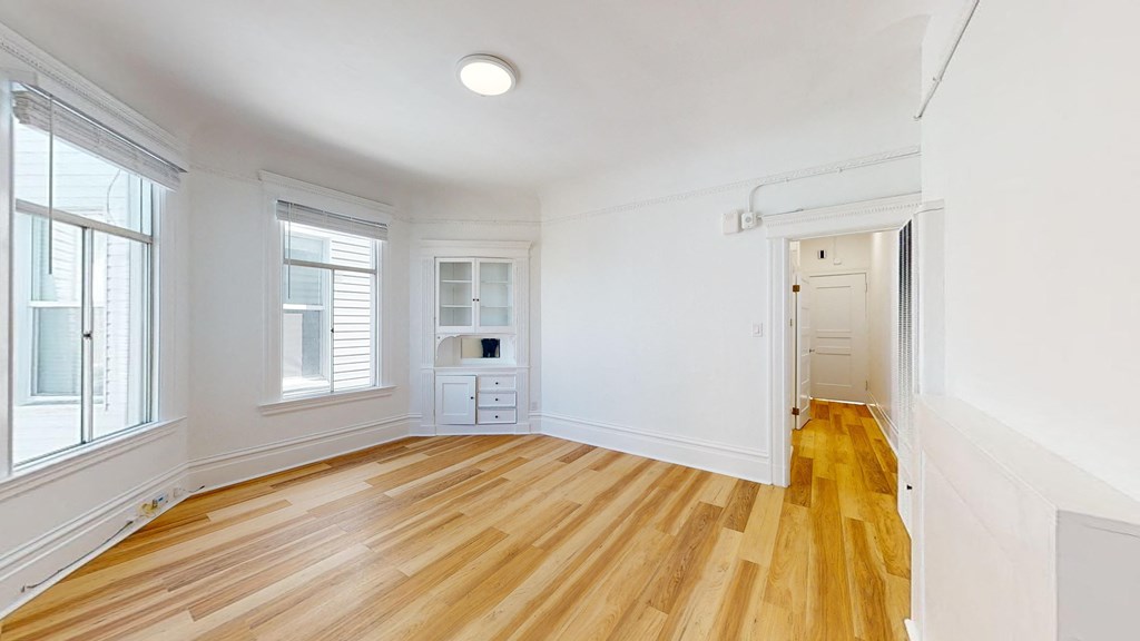 a living room with white walls and wood floors and a white door