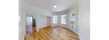 an empty living room with wood floors and a large window