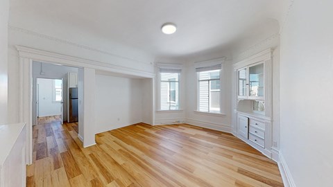 an empty living room with wood floors and a large window