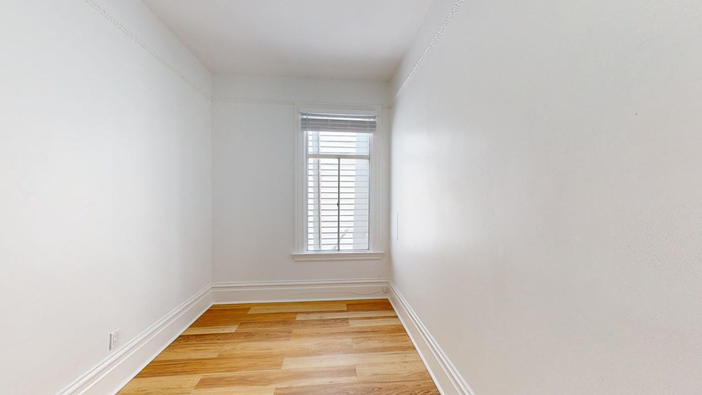 a room with white walls and a window and wooden floors
