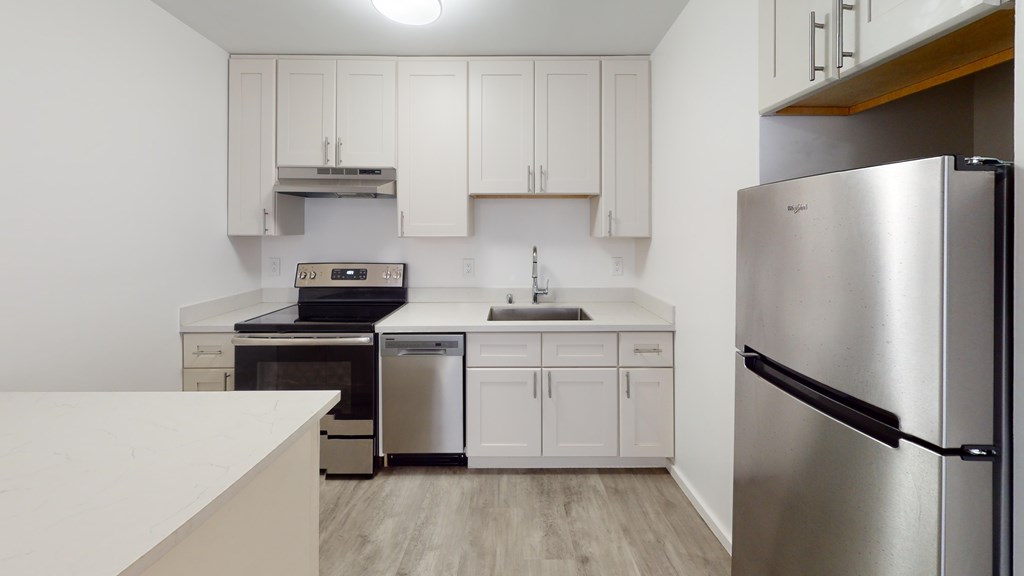 A kitchen with white cabinets and a stainless steel refrigerator.