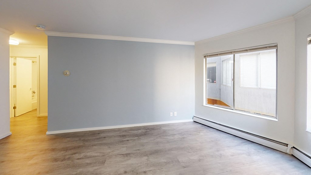 an empty living room with a large window and wood flooring
