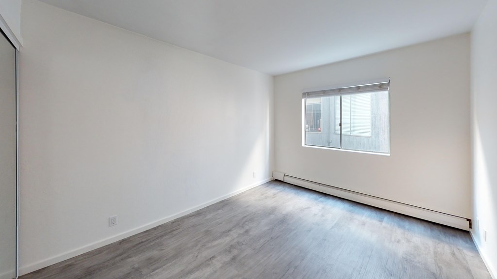 A room with a window and wooden flooring.