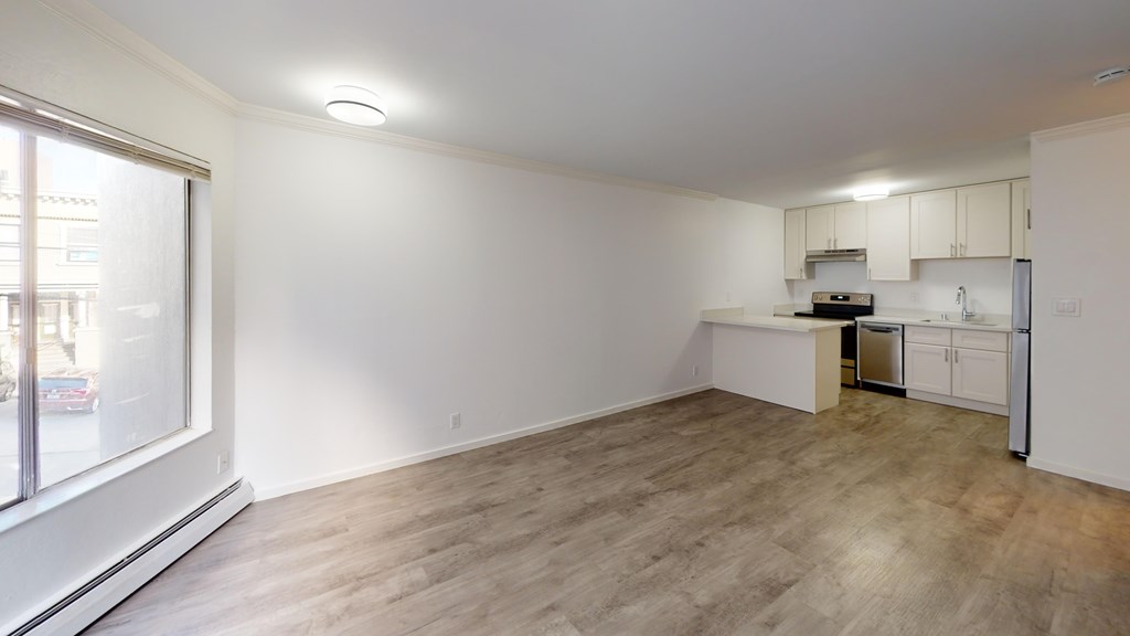A kitchen area with white cabinets and a wooden floor.