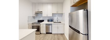 a white kitchen with stainless steel appliances and white cabinets