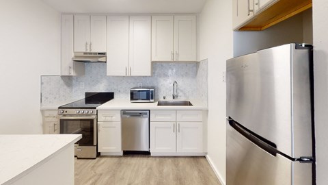a white kitchen with stainless steel appliances and white cabinets