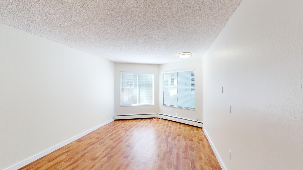 A room with wooden floors and two windows.