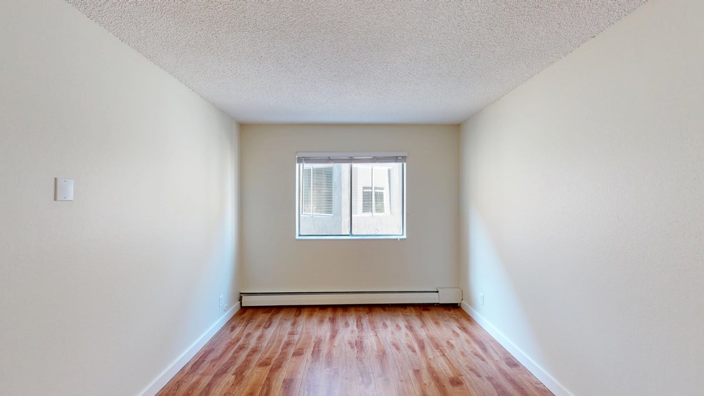 A room with a window and wooden floors.