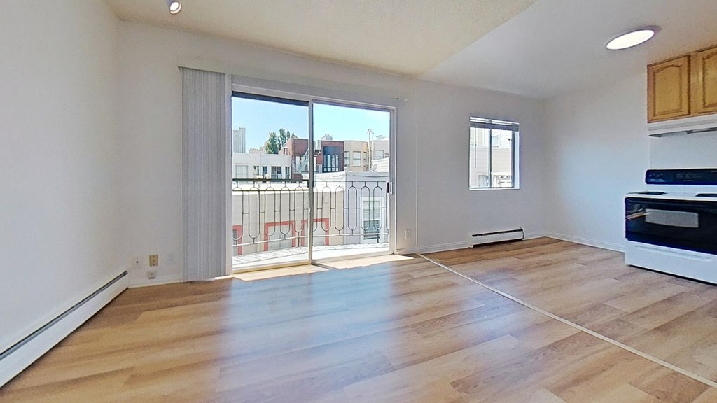 the living room of an apartment with wood flooring and a balcony