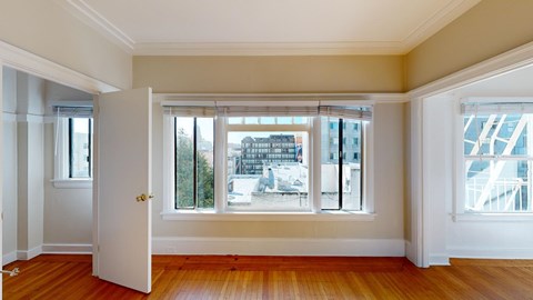 A room with a white door and a window with a view of a building outside.