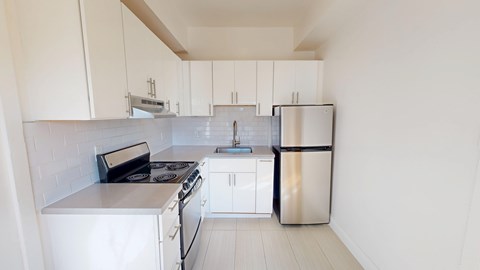 A white kitchen with a stove, sink, and refrigerator.