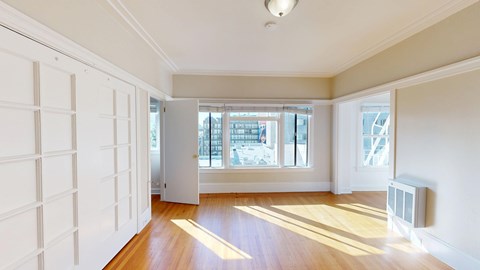 A room with white walls and wooden flooring with a window and a door.
