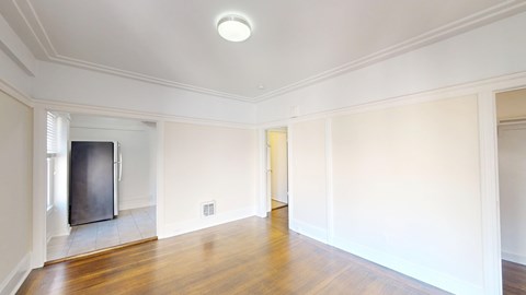 A spacious room with a wooden floor and white walls.
