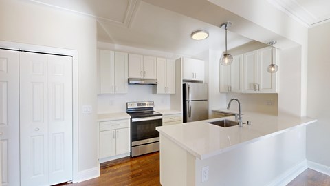 A white kitchen with a sink and a refrigerator.