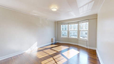 A room with a large window and wooden flooring.