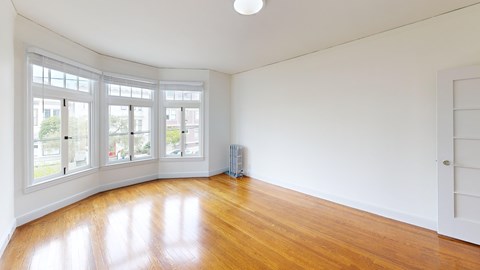 A room with a white wall and a wooden floor.