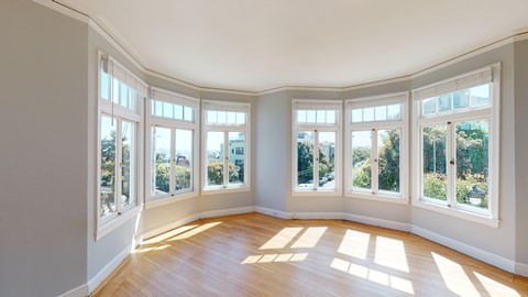 A sunny room with a view of trees through the windows.