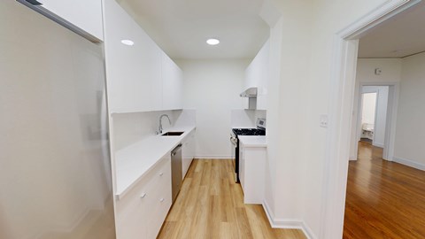 A kitchen with white cabinets and a black counter.