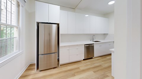 A modern kitchen with a stainless steel refrigerator and white cabinets.