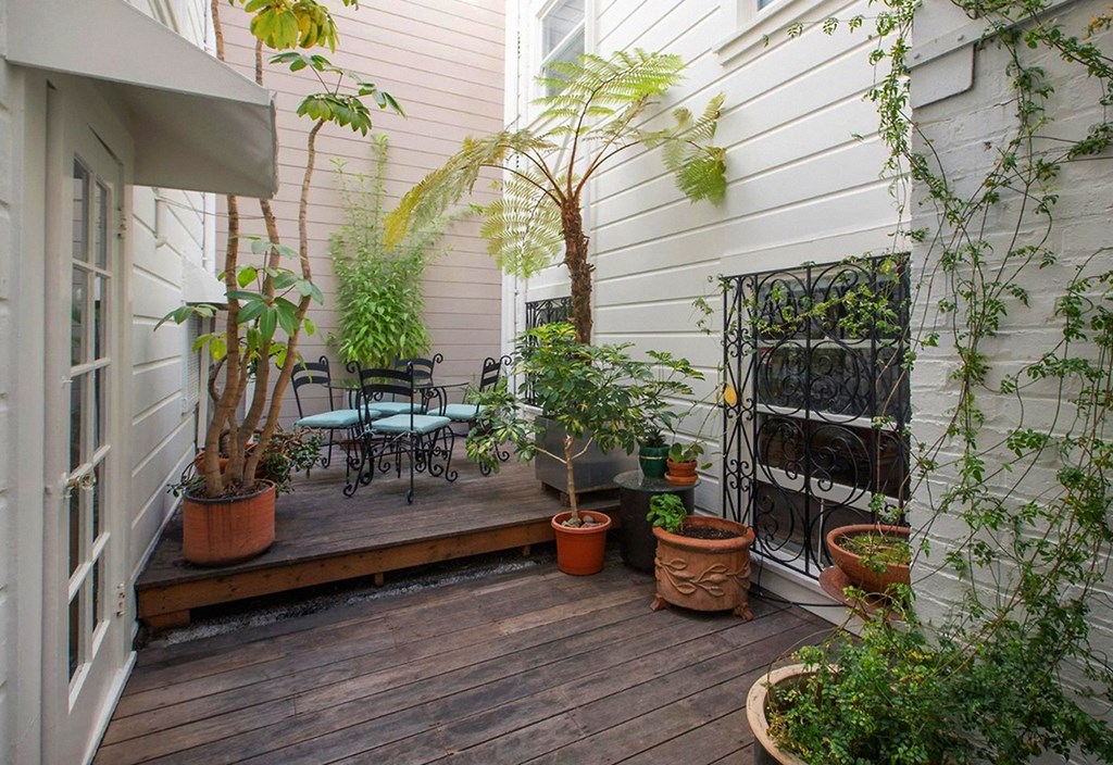 Wooden deck surrounded by a variety of potted plants and trees