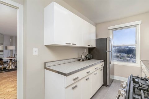 A kitchen with white cabinets and a window overlooking a cityscape.