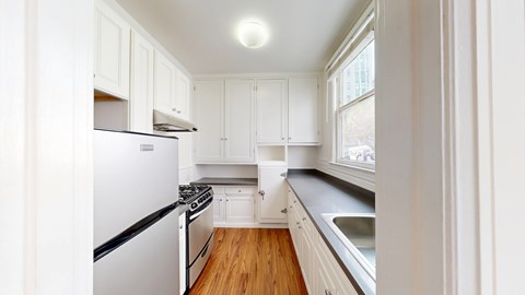 A kitchen with white cabinets and a stainless steel refrigerator.