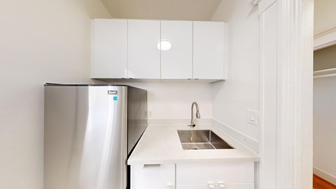 A kitchen with a stainless steel refrigerator and white cabinets.