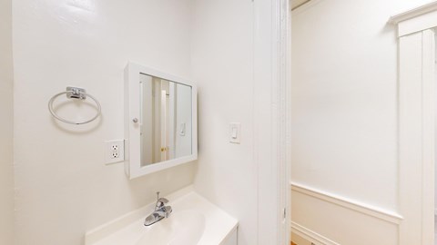 A white bathroom with a sink and mirror.