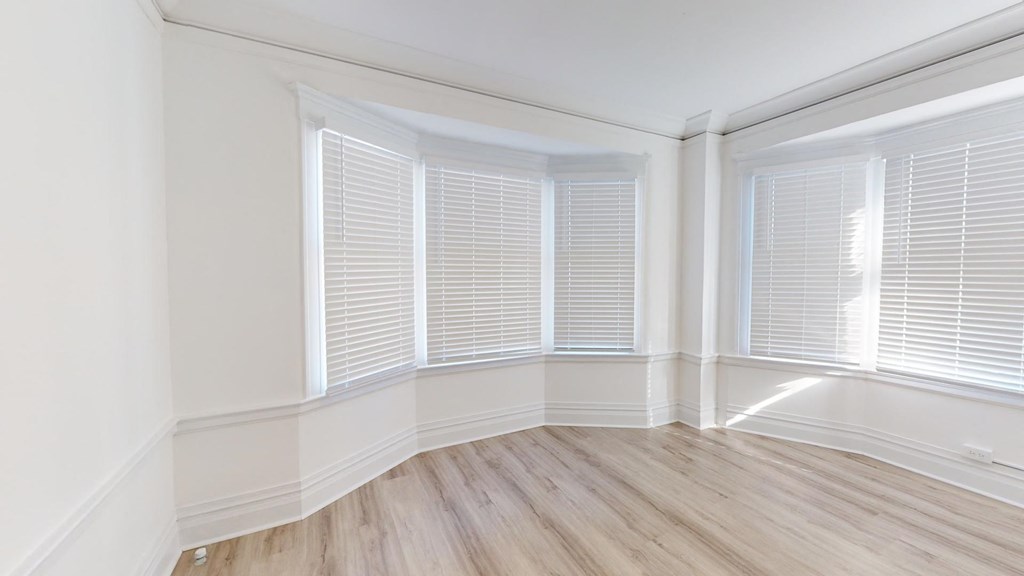 a living room with white plantation shuttered windows and wood floors