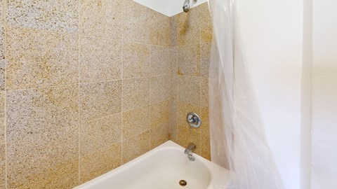 A bathroom with a beige tiled wall and a white bathtub.