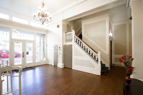 Hallway with a chandelier, staircase, and a vase of flowers