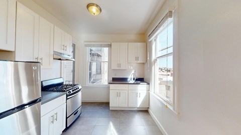 A kitchen with white cabinets and a stainless steel refrigerator.