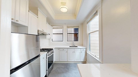 A kitchen with white cabinets and a stainless steel refrigerator.