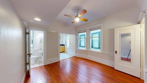 A room with a ceiling fan and hardwood floors.