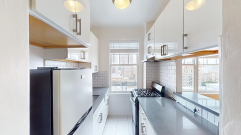 A modern kitchen with a black refrigerator and white cabinets.