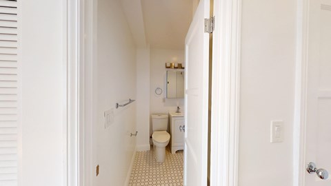 A white bathroom with a toilet, sink, and mirror.