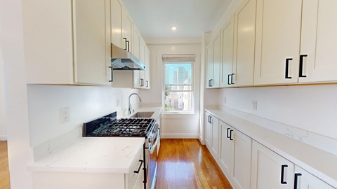 A kitchen with white cabinets and a wooden floor.