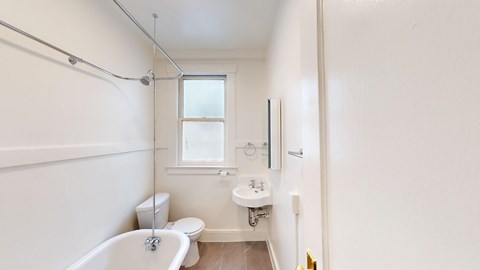 A white bathroom with a tub, sink, and toilet.