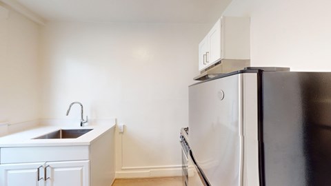 A black refrigerator sits in a kitchen next to a sink.
